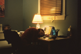 Girl sleeping with her head on a messy desk