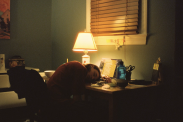 Girl sleeping with her head on a messy desk